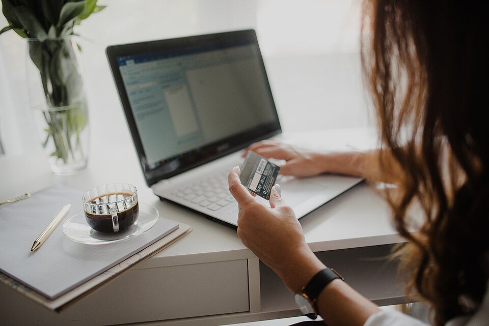 Close-up of a woman looking at a credit card while working on her laptop