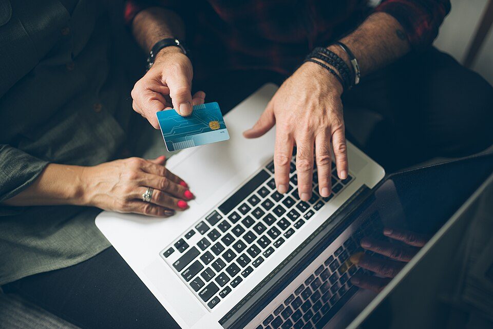 Senior couple at home checking finance on credit card from above
